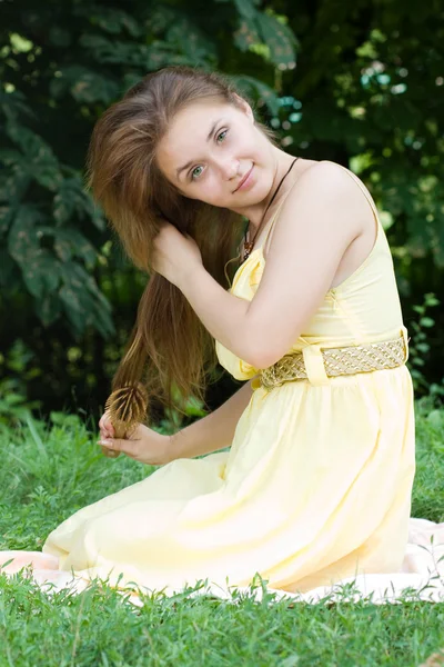 Дівчина розчісує її довге волосся, сидячи на відкритому повітрі — стокове фото