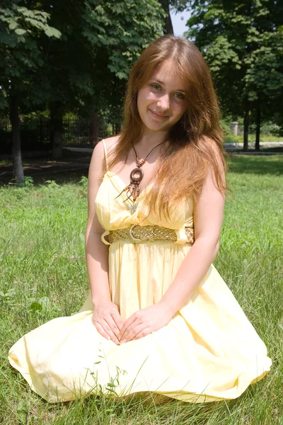 公園の緑の芝生に座っている若い女の子 — ストック写真