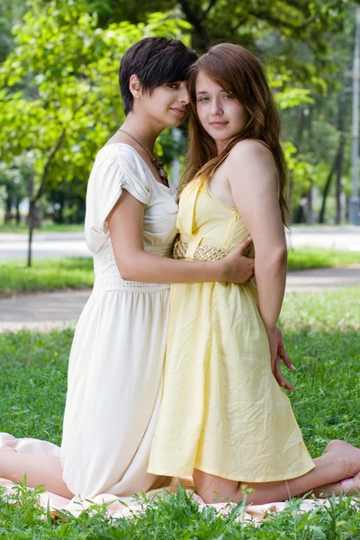 Girls embracing on the coverlet outdoors — Stock Photo, Image