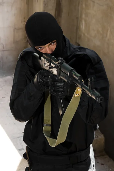 Soldado em uniforme preto com rifle — Fotografia de Stock