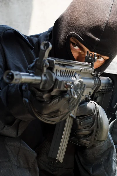 Soldaat in zwart pak met geweer — Stockfoto