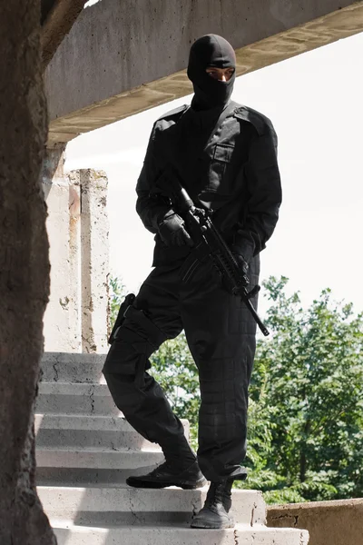 Soldado em uniforme preto com rifle — Fotografia de Stock