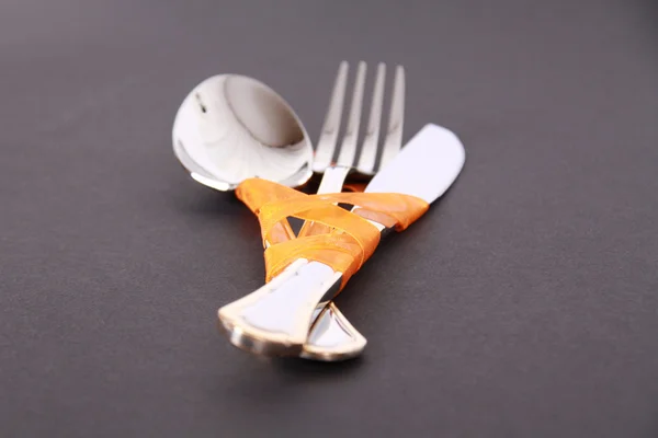 Fork, knife and spoon with orange ribbon — Stock Photo, Image