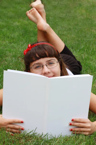Jenta med briller leser boka. – stockfoto