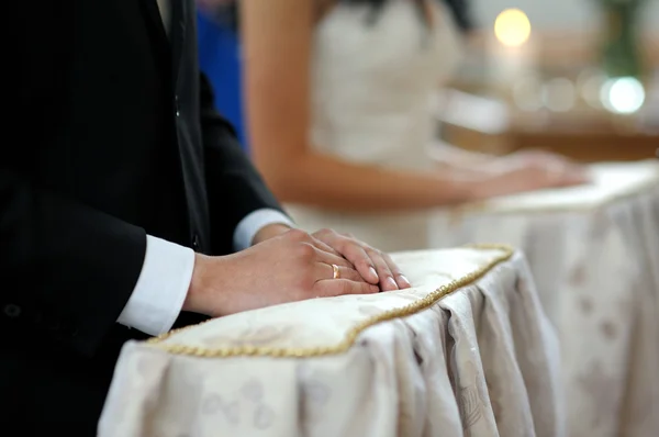 Руки жениха крупным планом во время церковной церемонии — стоковое фото