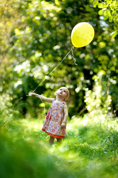 Sarı balon ile küçük bebek kız — Stok fotoğraf
