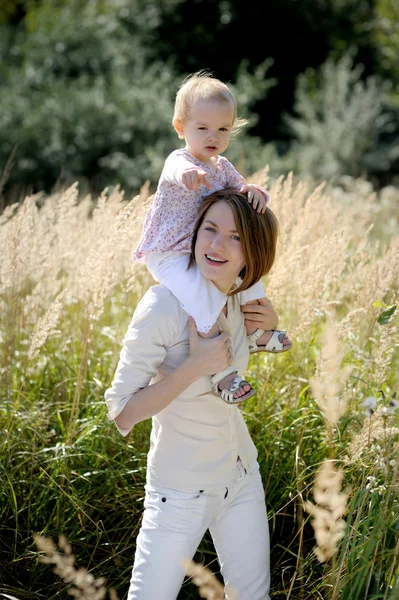 Moeder met een baby op haar schouders wijzend op — Stockfoto