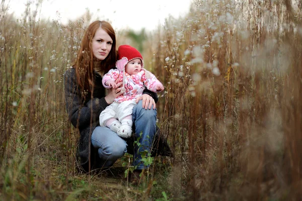 Jonge moeder en haar baby in een weide — Stockfoto
