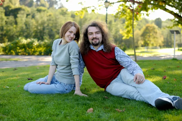 Jovem casal sentado na grama em um parque — Fotografia de Stock