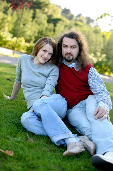 Молодая пара, сидящая на траве — стоковое фото