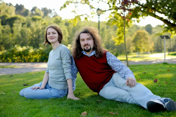 Jeune couple assis sur l'herbe — Photo