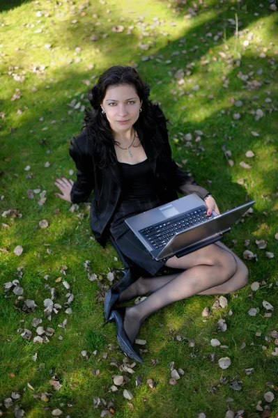 Giovane signora in un parco con un portatile — Foto Stock
