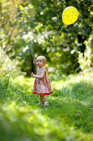 Pequena menina com um balão amarelo — Fotografia de Stock