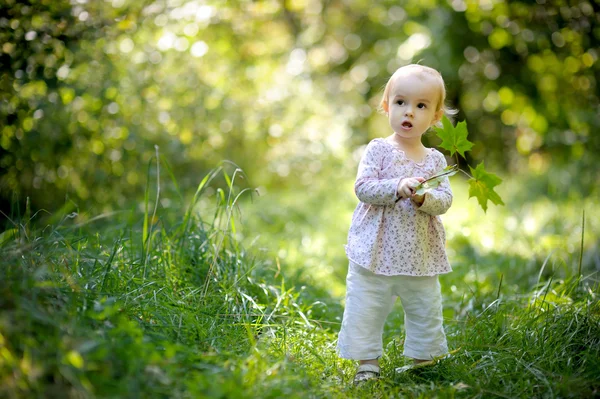 Lilla baby i skogen med lönnar lämnar — Stockfoto