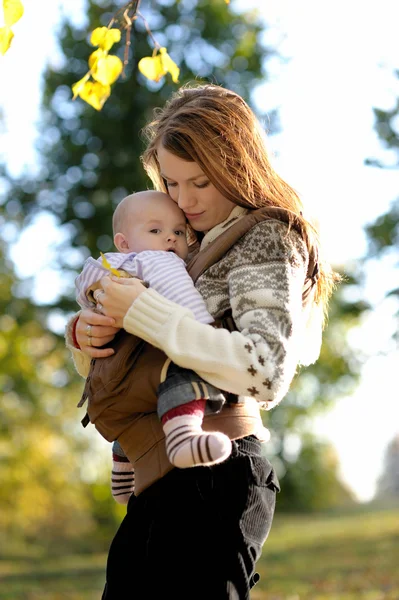 Jonge moeder met haar baby in een drager — Stockfoto