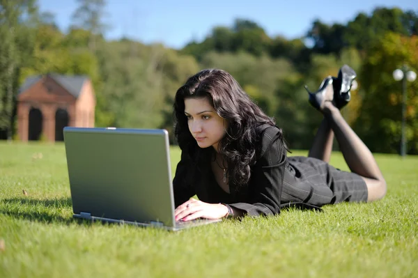 Ung dam med en bärbar dator i en park — Stockfoto