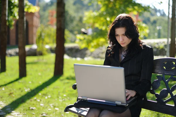 Ung dam med en bärbar dator i en park — Stockfoto