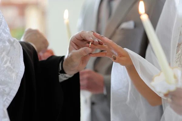 Sacerdote poniendo el anillo en el dedo de la novia — Foto de Stock