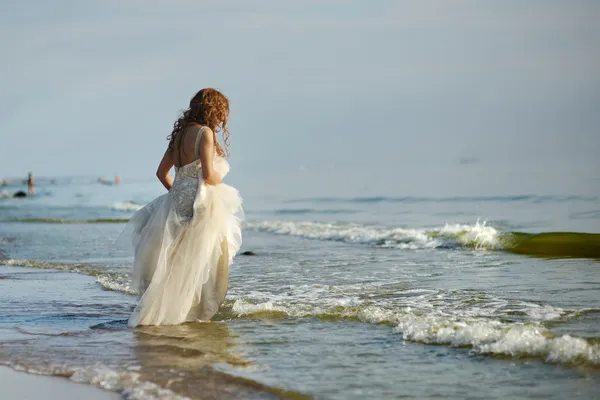 Nevěsta kráčí podél pobřeží — Stock fotografie