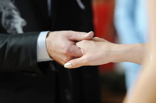 Brud- och brudgummen håller varandra i handen — Stockfoto