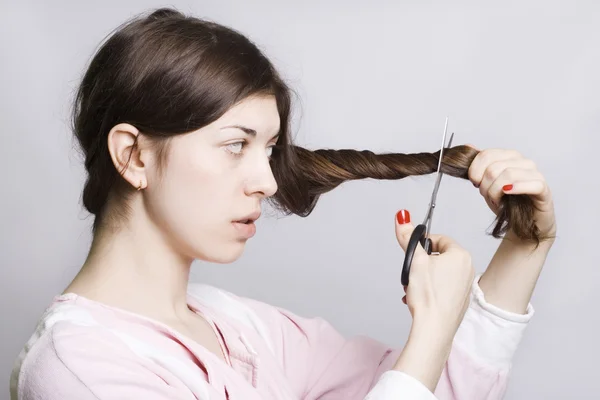Jovem mulher atraente está cortando seu h — Fotografia de Stock