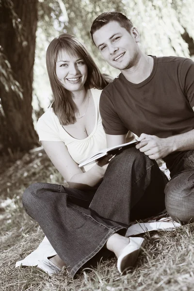 Jovem casal feliz lendo um livro — Fotografia de Stock