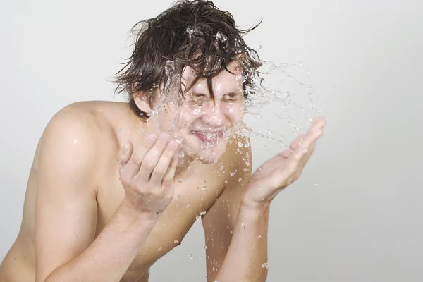 A fiatalember fröccsenő víz az arcán — Stock Fotó