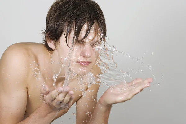 Junger Mann spritzt sich Wasser ins Gesicht — Stockfoto