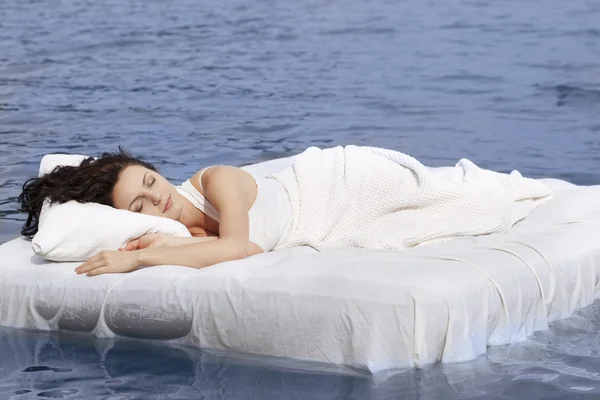 Woman sleeping on the bed in the sea Stock Picture