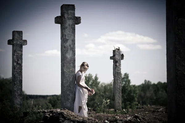 Грустная девушка возле креста — стоковое фото