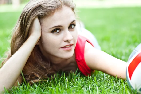Menina atraente jazia na grama — Fotografia de Stock