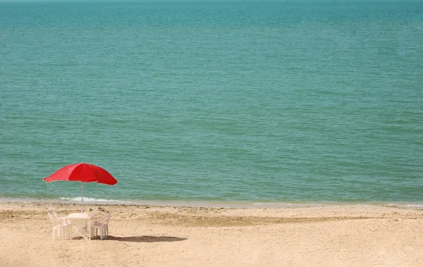 Tisch mit Sonnenschirmen am Strand — Stockfoto