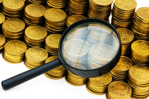 Stapel van munten en vergrootglas — Stockfoto