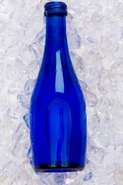 Grön flaska vatten på isbitar — Stockfoto