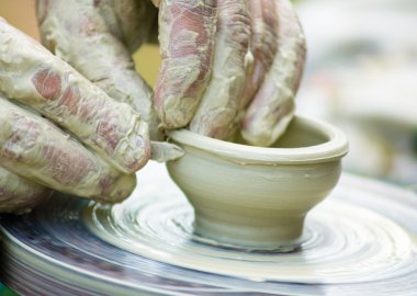 Potters hands creating a clay masterpiece at the turning wheel. clipart