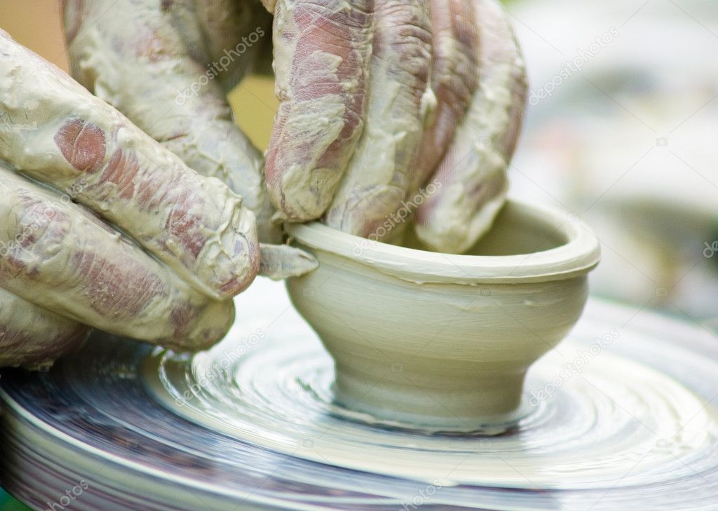 Potters hands creating a clay masterpiece at the turning wheel.