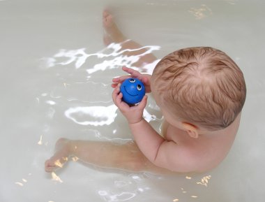 Baby with smile toy in bath clipart