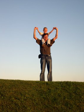 Father with son on shoulders on sundown clipart