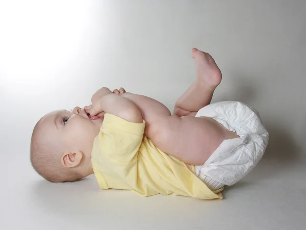 Bebê mente e chupa um dedo do pé — Fotografia de Stock