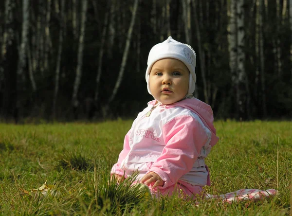 Bebé sentarse en la hierba en chaqueta y sombrero —  Fotos de Stock