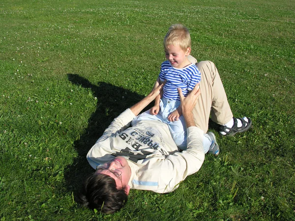 Сын на отце лежит на траве — стоковое фото