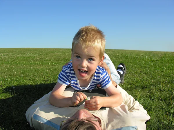 Son lie on ather on green grass — Stock Photo, Image