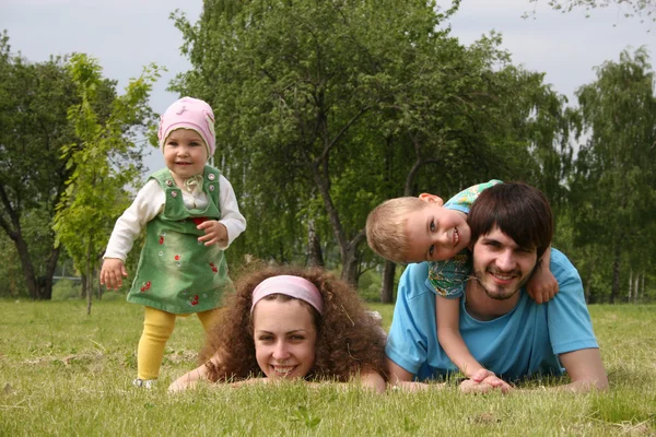 Familie van vier op gras — Stockfoto