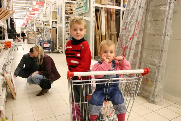 Дети в магазинной тележке и пара — стоковое фото