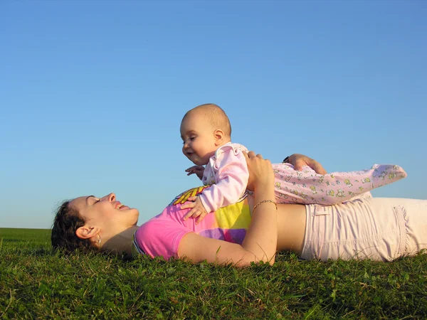 Mãe com bebê no pôr do sol mentira do lado — Fotografia de Stock