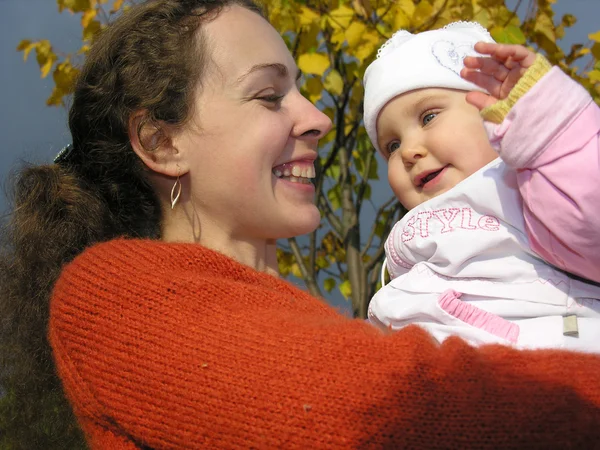 Enfrenta mãe com bebê em folhas de outono — Fotografia de Stock