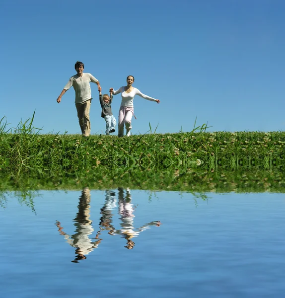 Семья на траве под голубым небом — стоковое фото