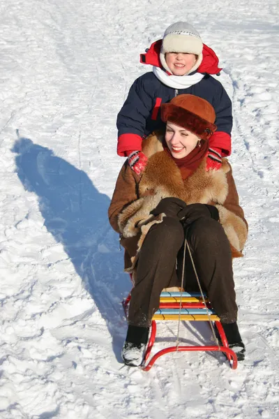 Зимний ребенок с матерью на санях — стоковое фото
