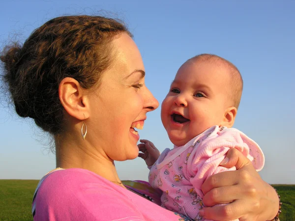 Faces mother with baby on sunset — Stock Photo, Image