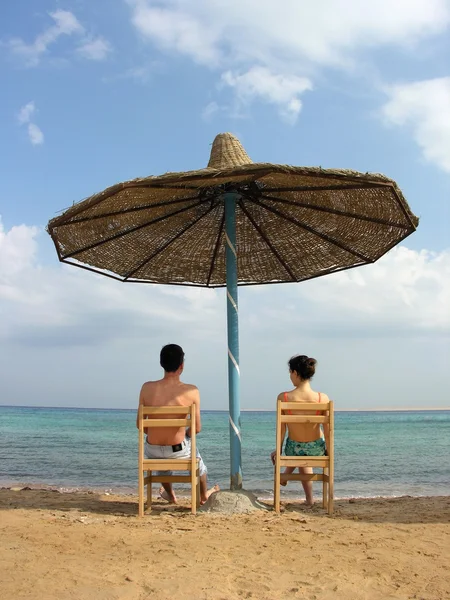 Para pod parasolem. morze. — Zdjęcie stockowe